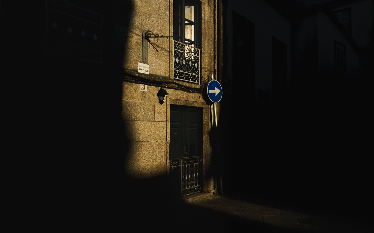 Fachadas de calle de Santiago en la que la luz ilumina una señal de obligatoriedad del sentido.