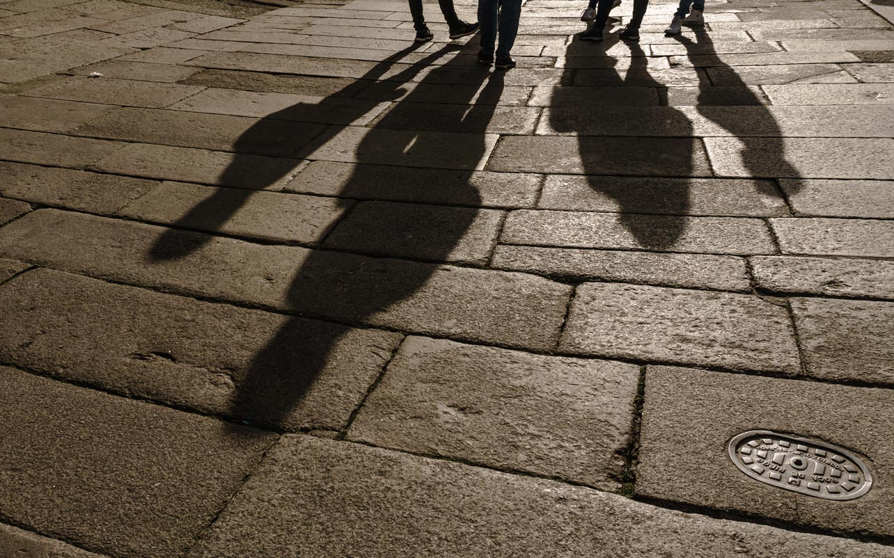 Composición artística de sombras de personas en el pavimento de piedra de la zona monumental